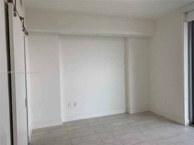 unfurnished room featuring a barn door and light hardwood / wood-style floors