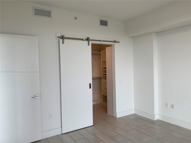 unfurnished room featuring a barn door and light wood-type flooring