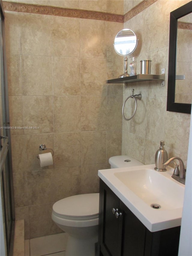 bathroom with vanity, toilet, and tile walls