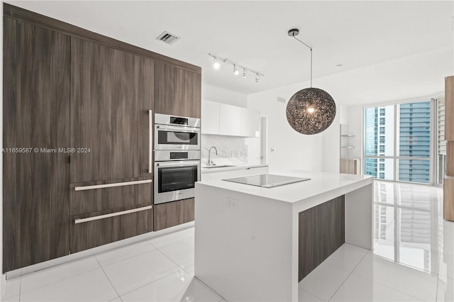 kitchen featuring stainless steel double oven, decorative light fixtures, sink, black electric cooktop, and white cabinets