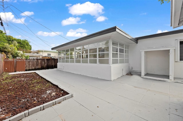 view of property exterior with a patio area and a sunroom