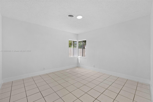 tiled empty room with a textured ceiling