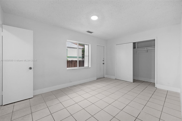 unfurnished bedroom featuring a closet, light tile patterned floors, and a textured ceiling