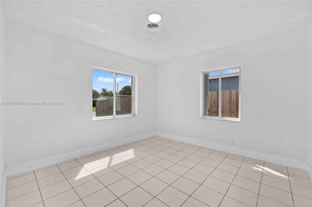 tiled empty room featuring a textured ceiling