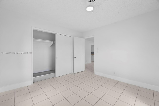 unfurnished bedroom with light tile patterned floors, a textured ceiling, and a closet