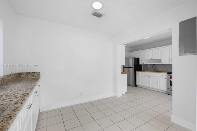 kitchen with electric panel, sink, light tile patterned floors, appliances with stainless steel finishes, and white cabinetry