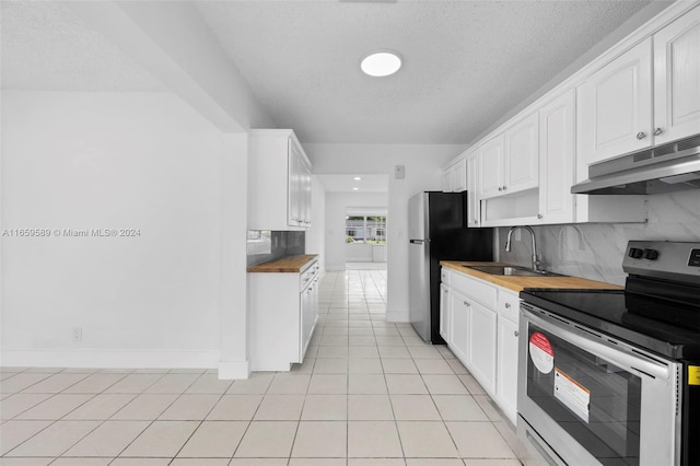 kitchen with decorative backsplash, stainless steel electric range oven, sink, light tile patterned floors, and white cabinetry