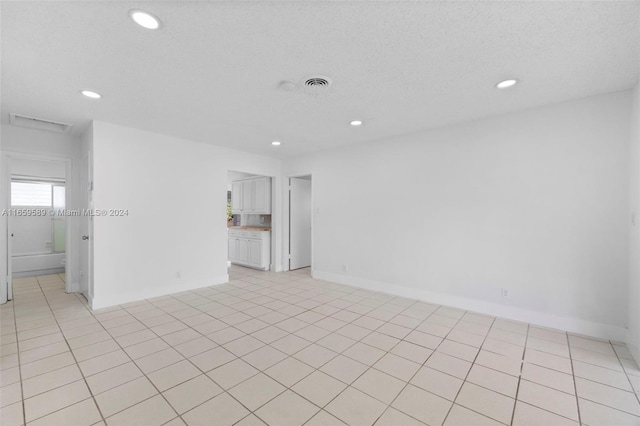 unfurnished room featuring light tile patterned floors and a textured ceiling