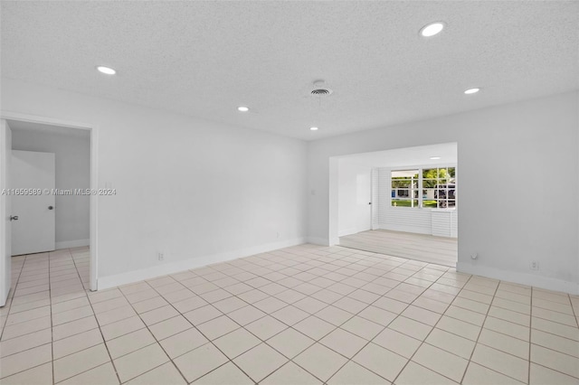 tiled empty room with a textured ceiling