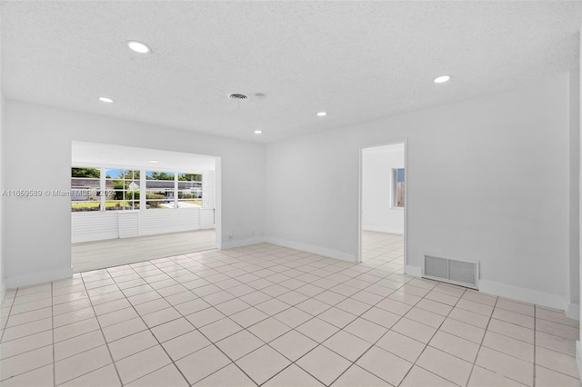 tiled empty room with a textured ceiling