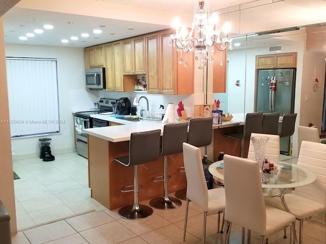 kitchen with a notable chandelier, appliances with stainless steel finishes, hanging light fixtures, kitchen peninsula, and light tile patterned flooring