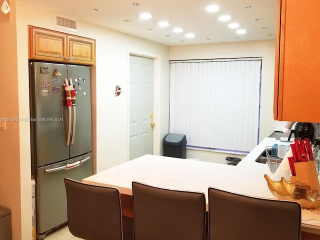 kitchen featuring kitchen peninsula, stainless steel refrigerator, and a breakfast bar