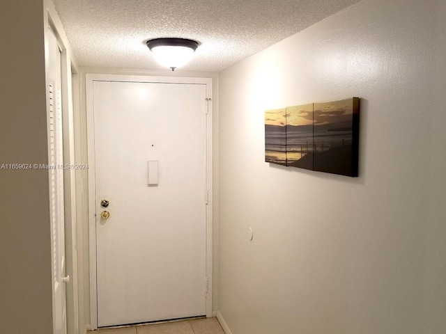 doorway to outside featuring a textured ceiling and light tile patterned floors