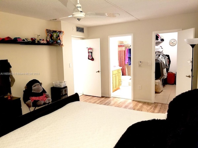 bedroom with ensuite bath, light hardwood / wood-style floors, a closet, ceiling fan, and a textured ceiling