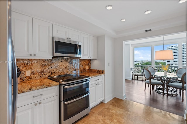 kitchen featuring dark stone countertops, appliances with stainless steel finishes, white cabinetry, and decorative light fixtures