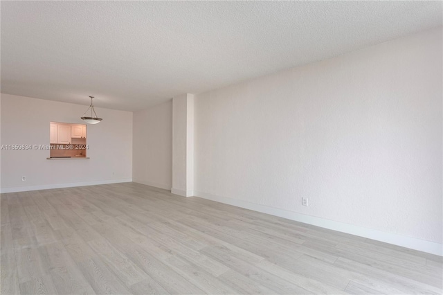 unfurnished living room with light wood-type flooring and a textured ceiling