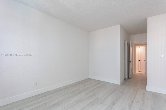 spare room with a textured ceiling and light hardwood / wood-style flooring