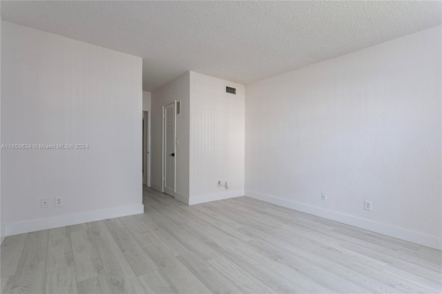 spare room featuring light hardwood / wood-style floors and a textured ceiling