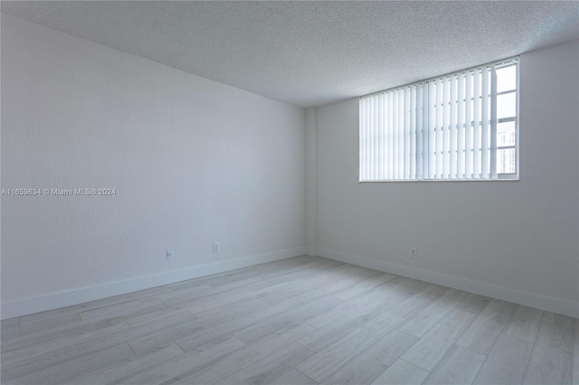 unfurnished room featuring light hardwood / wood-style floors and a textured ceiling