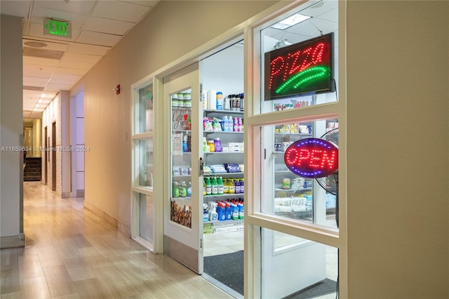 doorway to outside featuring a healthy amount of sunlight, a drop ceiling, and light hardwood / wood-style flooring