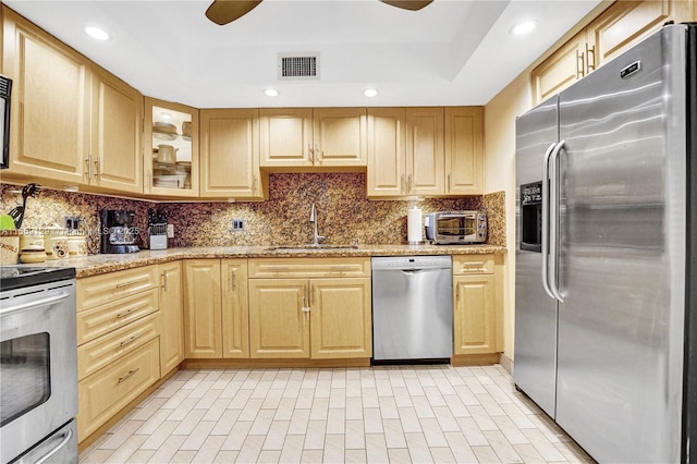 kitchen with sink, light brown cabinets, stainless steel appliances, light stone countertops, and backsplash