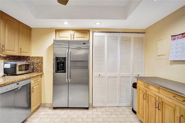 kitchen with light brown cabinetry, a tray ceiling, and stainless steel appliances