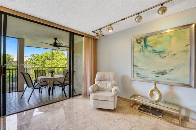 living area featuring expansive windows, ceiling fan, and a textured ceiling