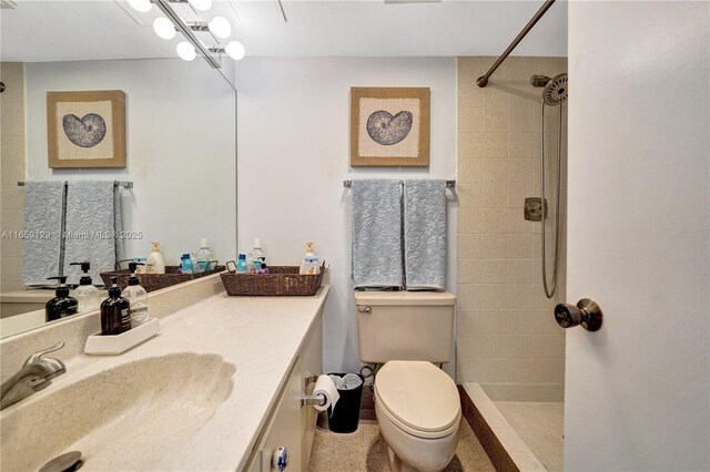 bathroom featuring vanity, tiled shower, and toilet