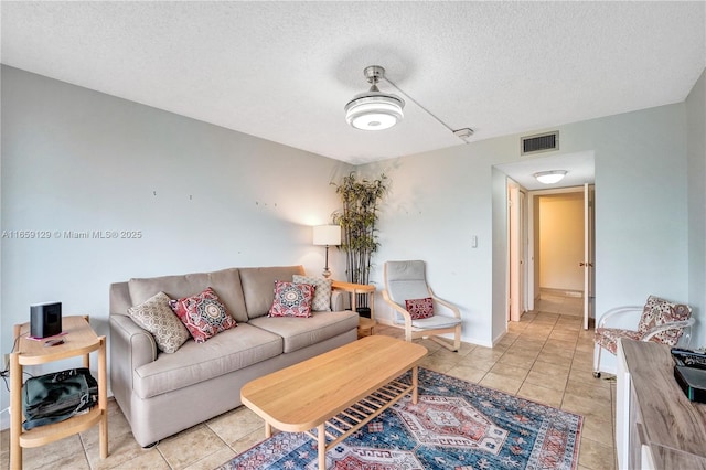 living room with a textured ceiling and light tile patterned floors