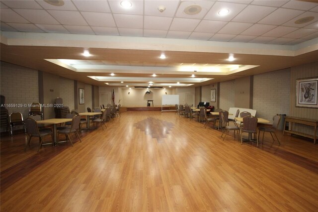 miscellaneous room with brick wall and light hardwood / wood-style flooring