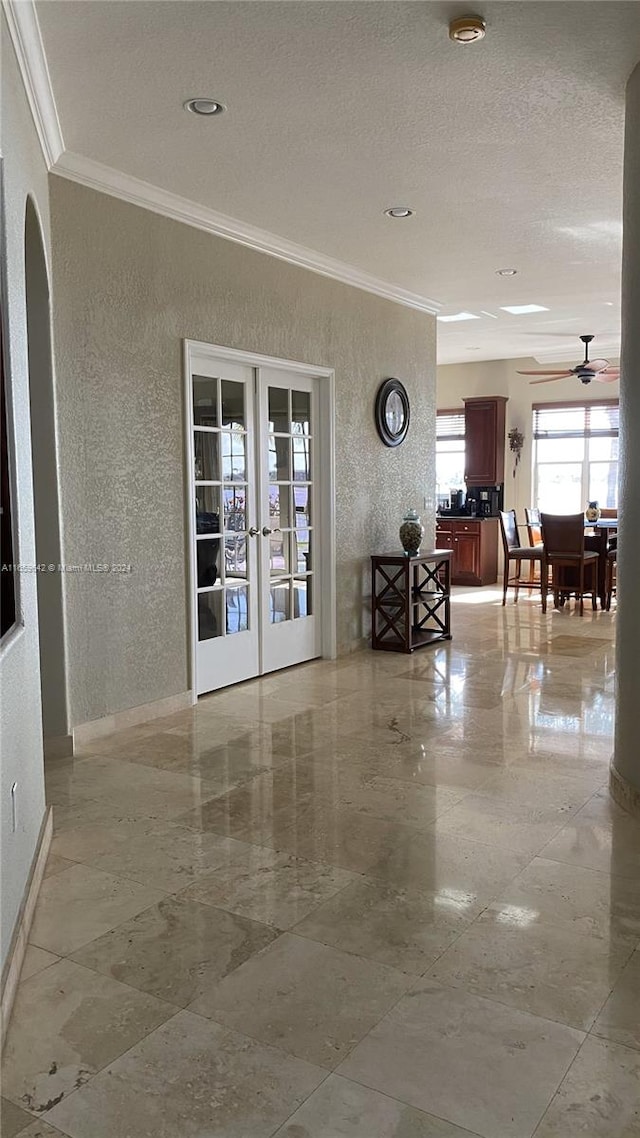 interior space with ornamental molding, french doors, a textured ceiling, and ceiling fan