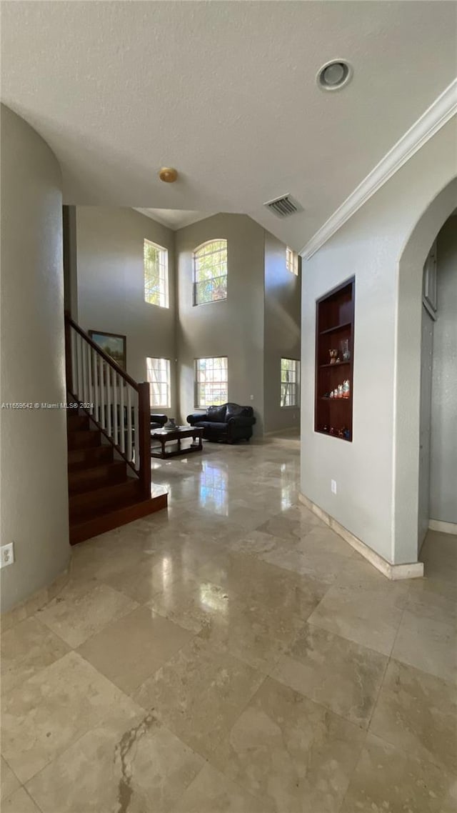 entrance foyer featuring crown molding, vaulted ceiling, and a textured ceiling