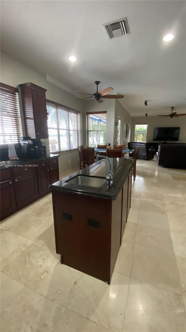 kitchen featuring light tile patterned floors, sink, an island with sink, and ceiling fan