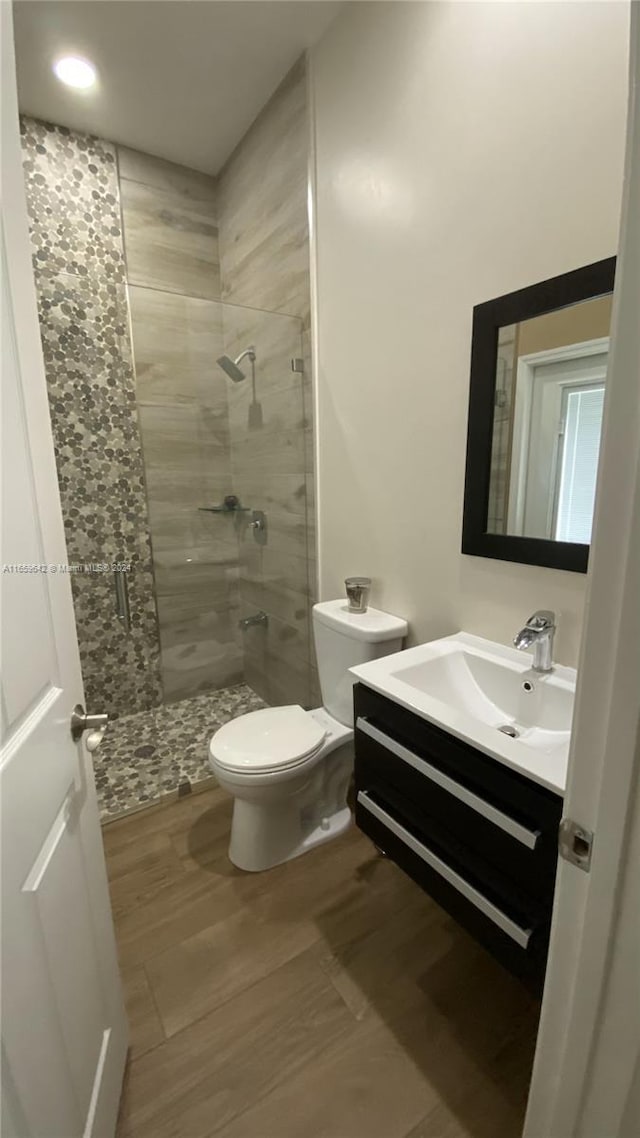 bathroom featuring vanity, toilet, wood-type flooring, and walk in shower