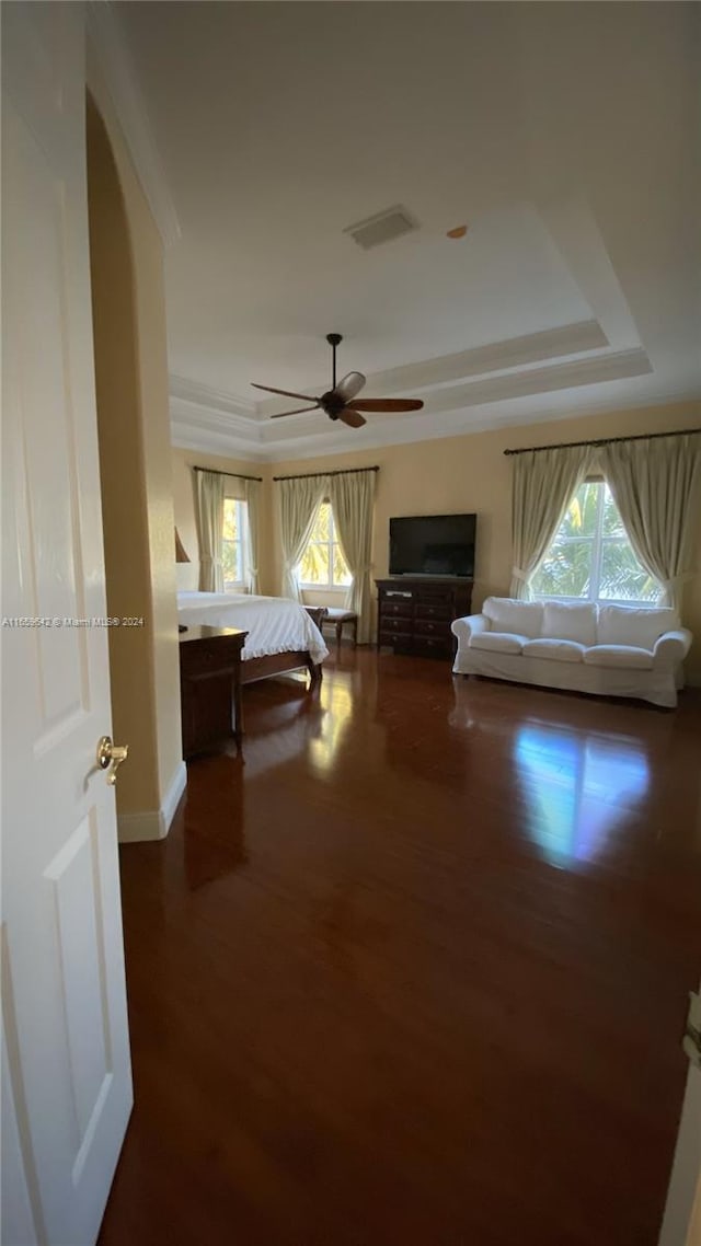 bedroom featuring a tray ceiling, multiple windows, and dark hardwood / wood-style floors