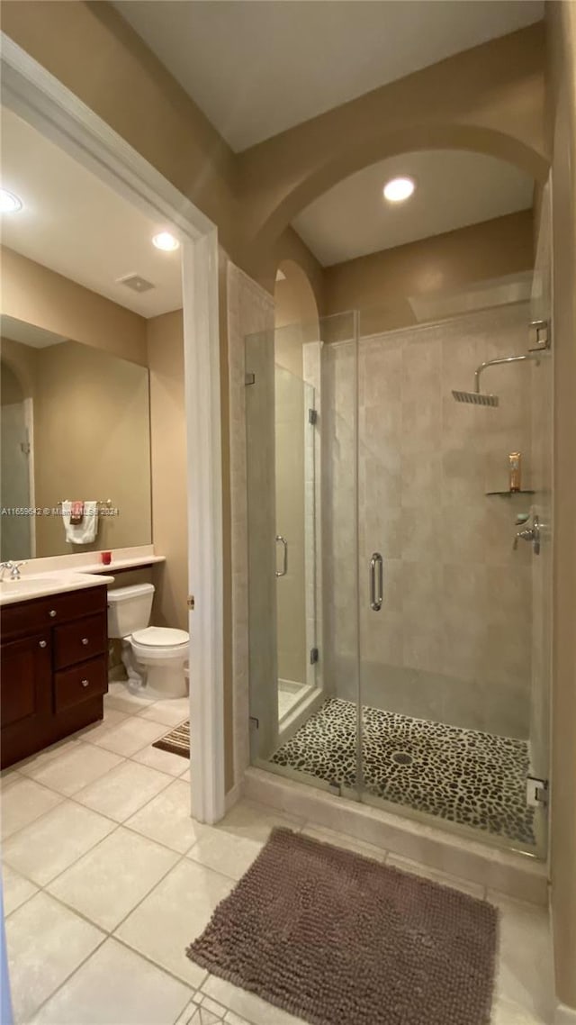 bathroom with tile patterned flooring, vanity, toilet, and walk in shower