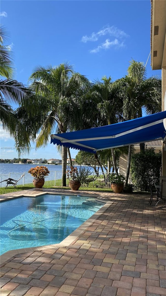 view of swimming pool with a water view and a patio