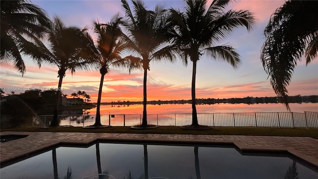 pool at dusk featuring a water view