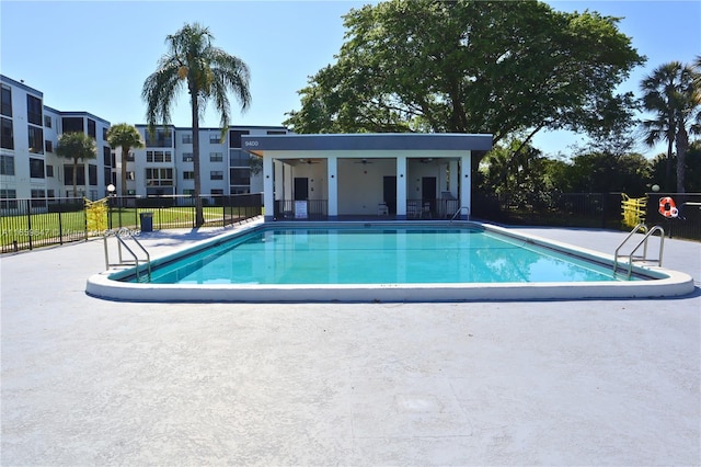 community pool with a patio area, fence, and a ceiling fan