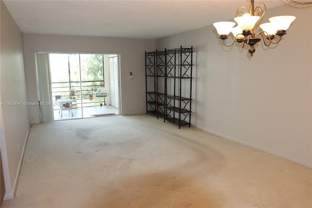 empty room featuring a textured ceiling, an inviting chandelier, and carpet floors