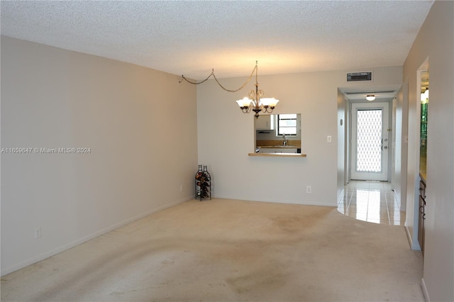 spare room with a textured ceiling, a chandelier, sink, and carpet floors