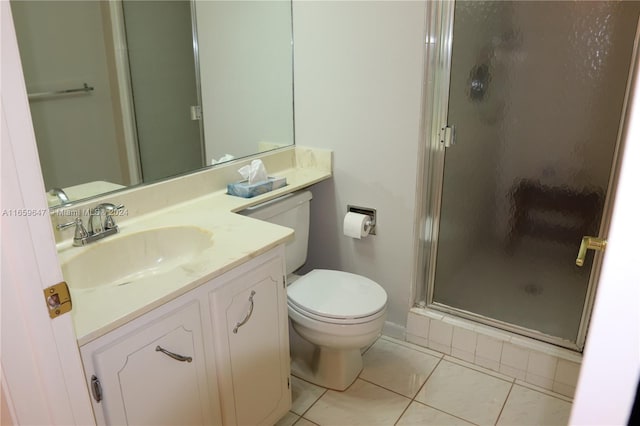 bathroom with tile patterned flooring, vanity, toilet, and a shower with shower door