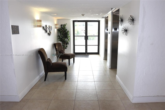 hallway featuring french doors, light tile patterned floors, a textured ceiling, a wall of windows, and baseboards