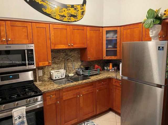 kitchen with light tile patterned floors, appliances with stainless steel finishes, light stone counters, sink, and decorative backsplash