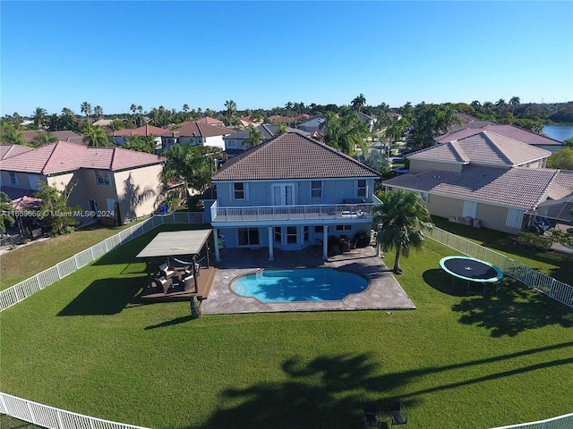 view of swimming pool featuring a lawn, a trampoline, and a patio