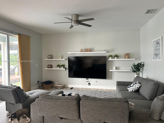 living room with ceiling fan, wood-type flooring, and a textured ceiling