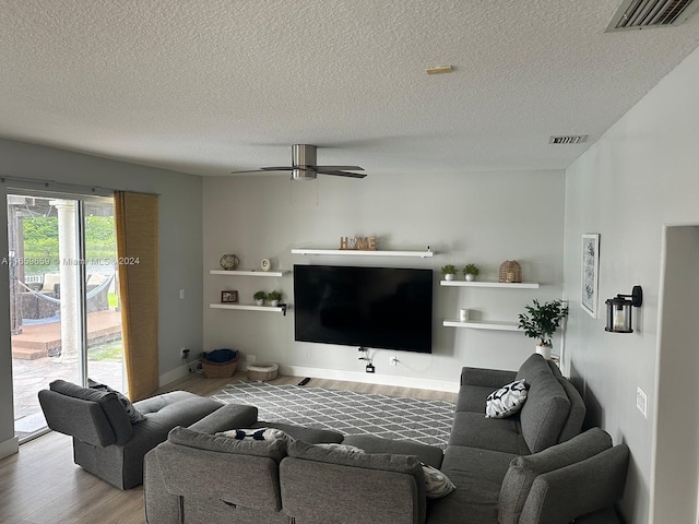 living room with ceiling fan, wood-type flooring, and a textured ceiling