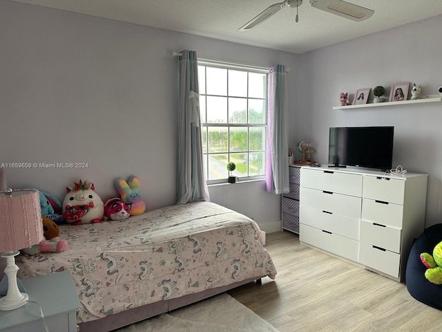 bedroom with a textured ceiling, light hardwood / wood-style floors, and ceiling fan