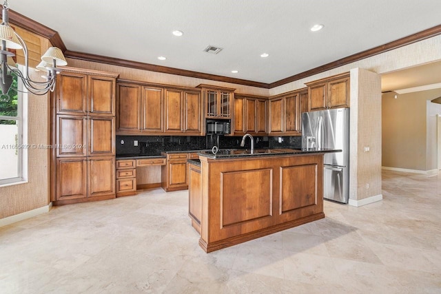 kitchen featuring a kitchen island with sink, stainless steel fridge, ornamental molding, and dark stone countertops