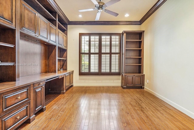 unfurnished office with light wood-type flooring, built in desk, ornamental molding, and ceiling fan